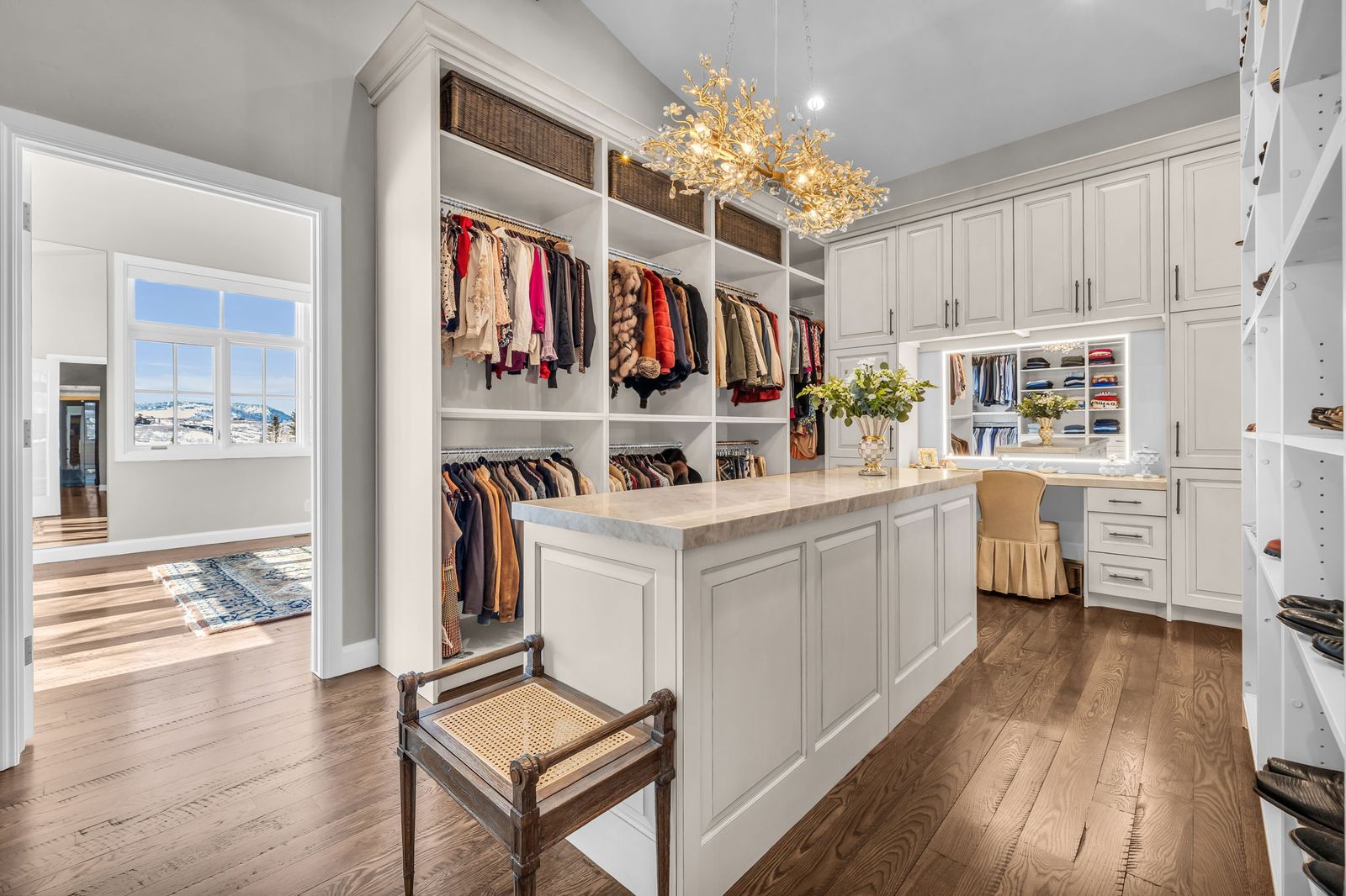 Bright custom dressing room with a chandelier, island and open shelving