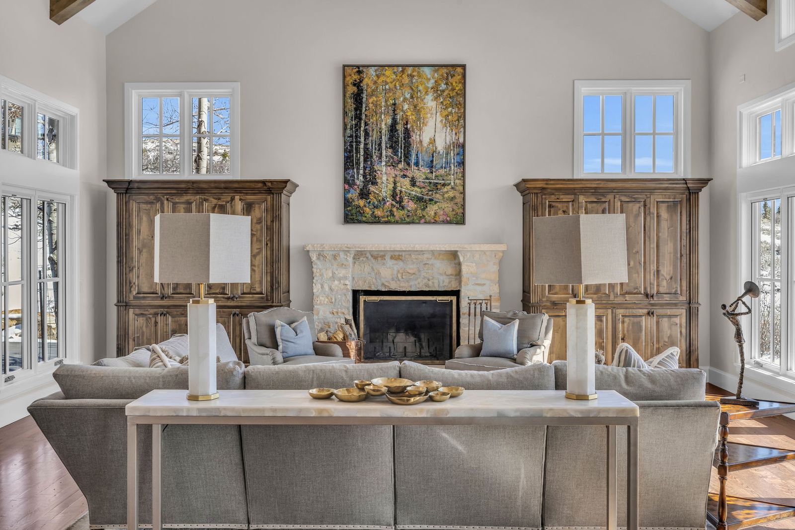 Living room with stone fireplace flanked by carved wood armoires